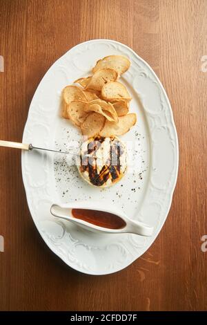 From above delicious grilled chicken burger with crispy baked bread chips and BBQ sauce on plate on table Stock Photo