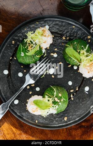 From above tasty appetizing Brussels sprouts with cream sauce and herbs on black plate in restaurant Stock Photo