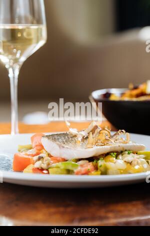 From above of fillet fish with small square slices of peppers on plate in restaurant Stock Photo