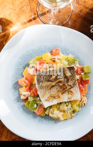 From above of fillet fish with small square slices of peppers on plate in restaurant Stock Photo