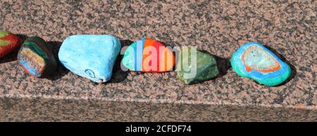 brightly painted pebbles on a brick wall Stock Photo