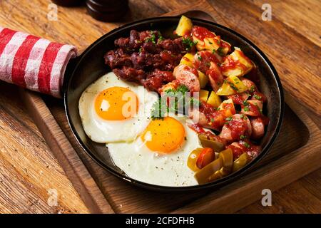 Fried eggs with vegetables in pan Stock Photo