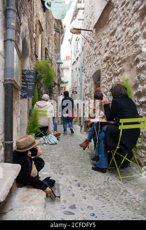 Saint-Paul-de-Vence  A tea for two in a quiet hiding place.Street narrow, space for a table and two chairs. The monkey in the hat sits on the stairs. Stock Photo