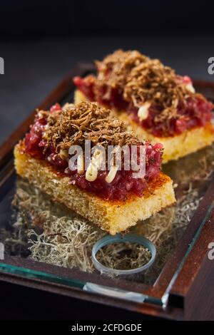 Sweet sponge cake with berry marmalade and chocolate curls placed on box with dry moss Stock Photo