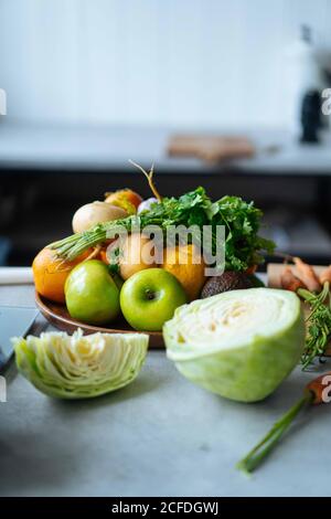Bunch of various fresh fruits and vegetables placed on counter during lunch preparation in modern kitchen Stock Photo