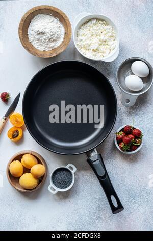 Top view of assorted fresh ingredients for delicious dessert preparation placed around empty frying pan on table in kitchen Stock Photo