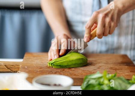 Woman cutting avocado on cutting board Stock Photo