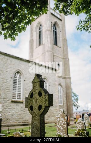 Grave stone in the form of a Celtic cross with St. Columba's Church, Drumcliff, Ireland Stock Photo