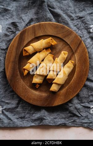 From above tasty crunchy appetizing croissants in wooden plate on linen on table Stock Photo