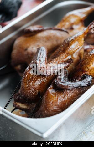 From above of cooked fried chickens on metal skewers in market stall Stock Photo