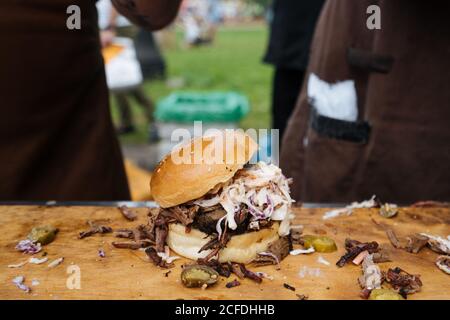 From above of burger of cucumber with cole slaw and beef in bun on table in marketplace Stock Photo