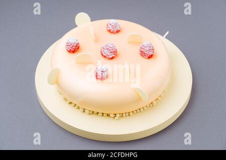 From above yummy cake with fresh raspberries and white chocolate icing placed on round board against gray background Stock Photo