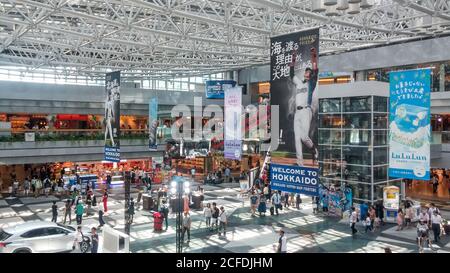 Sapporo, Hokkaido, Japan - Crowded tourists at Domestic terminal atrium of New Chitose Airport. Advertising hanging banners about Nippon-Ham Fighters. Stock Photo