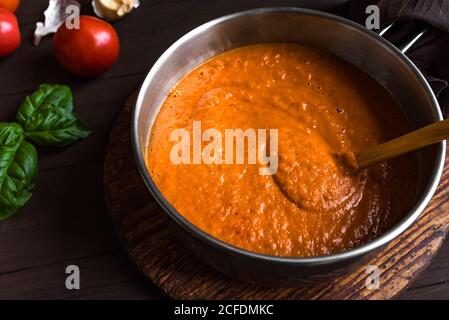 Homemade tomato sauce in cooking pan and ingredients close up. Making organic italian tomato sauce or soup. Stock Photo