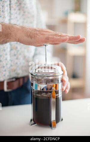 Close up of old man making coffee with a french press. Elderly person in the morning enjoying fresh brown cafe espresso cup caffeine from vintage mug, filter relax refreshment Stock Photo