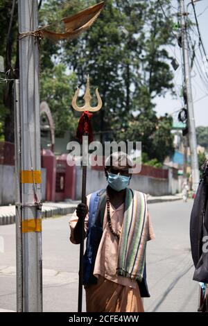 A Sadhu wearing mask going on the road, facing camera. Stock Photo