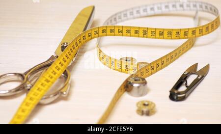 Tailor tools isolated on wooden background. Scissors, needle, Tailoring Meter, hand Stock Photo