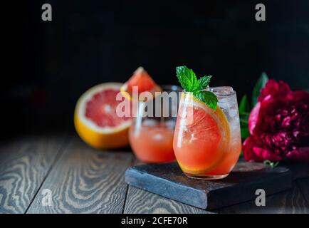A glass of freshly squeezed grapefruit juice and mint on a dark wooden table. Refreshing summer cocktail. Stock Photo