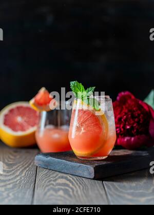 A glass of freshly squeezed grapefruit juice and mint on a dark wooden table. Refreshing summer cocktail. Stock Photo