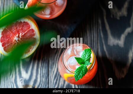 A glass of freshly squeezed grapefruit juice and mint on a dark wooden table. Refreshing summer cocktail. Stock Photo