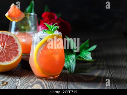 A glass of freshly squeezed grapefruit juice and mint on a dark wooden table. Refreshing summer cocktail. Stock Photo