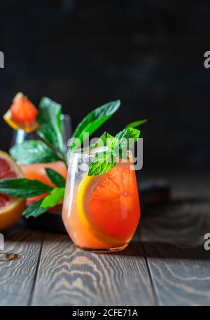 A glass of freshly squeezed grapefruit juice and mint on a dark wooden table. Refreshing summer cocktail. Stock Photo
