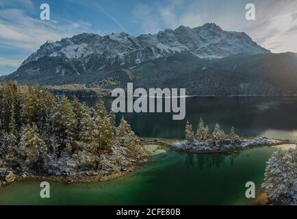 Eibsee in winter (beginning of winter), Braxenbucht with a view of Braxeninsel and Wetterstein Mountains with Zugspitze, lake shore, blue sky, Stock Photo