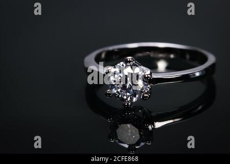 luxury wedding ring with big diamond crystal isolated on black background with reflect in the mirror. Stock Photo
