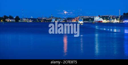 Beautiful sea view on Stockholm in dusk and ferry floating at Baltic Sea, Sweden. Moonlight sky. Stock Photo