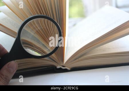 open book with magnifying glass over white background Stock Photo - Alamy