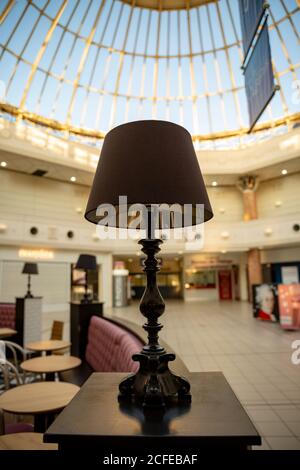 Bedside black table lamp on a small table on a blurry big Hall background. Stock Photo