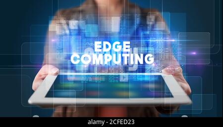 Young business person working on tablet and shows the inscription: EDGE COMPUTING Stock Photo