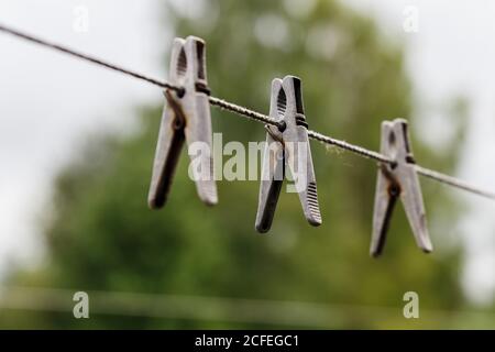 clothespins hanging on a rope. Three clothespins hang from a clothesline. Blurred background. Stock Photo