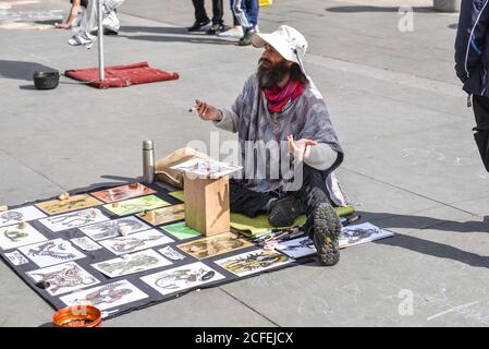 LONDON, UK - April 01, 2017: An unidentified street artist draws graphics on paper and presents it to tourists. Stock Photo