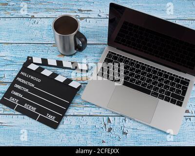 Coffee cup with laptop and cell phone and clapper movie on wood background top view Stock Photo