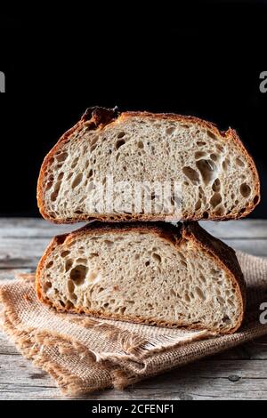 Pieces of tasty fresh bread falling on napkin on table against black background Stock Photo