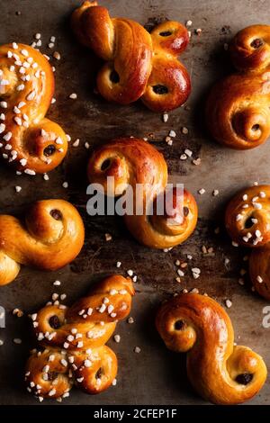 Top view of delicious homemade curly buns with raisin and sprinkles placed on wooden table Stock Photo