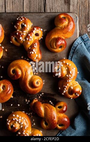 Top view of delicious homemade curly buns with raisin and sprinkles placed on wooden table Stock Photo