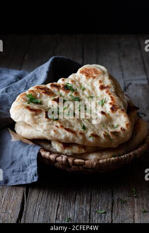 Plate with delicious naan bread and cloth napkin placed on weathered lumber table Stock Photo