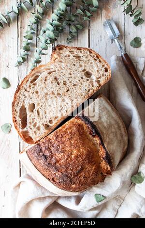 From above homemade fresh sourdough bread in tablecloth on wooden table Stock Photo