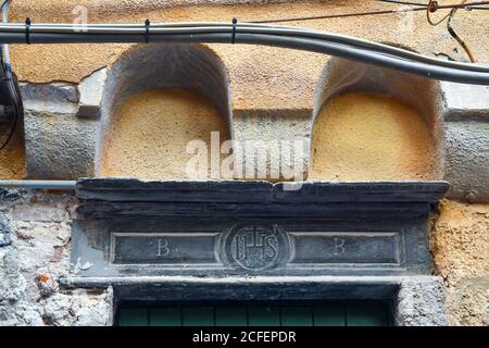 Close-up of a carved stone over the entrance door of a medieval building with the religious symbol IHS, greek acronym for Jesus, Porto Venere, Italy Stock Photo