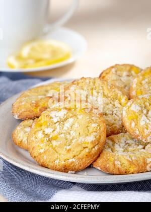 Lemon crinkle cookies on a plate with cup and sliced lemon in background Stock Photo