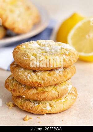 Stack of lemon crinkle cookies on a table with sliced lemon and cookie plate in background Stock Photo