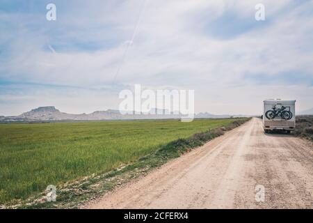 White trailer on empty road between fields with vegetation Stock Photo