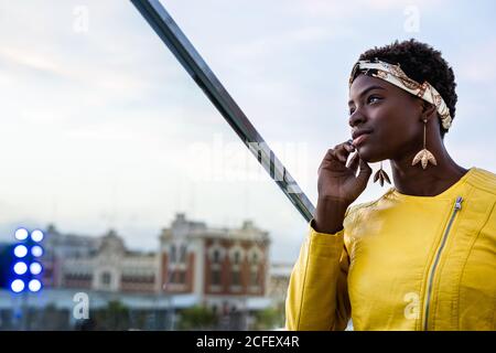 Side view of serene African American Woman chilling on glass balcony and looking away Stock Photo