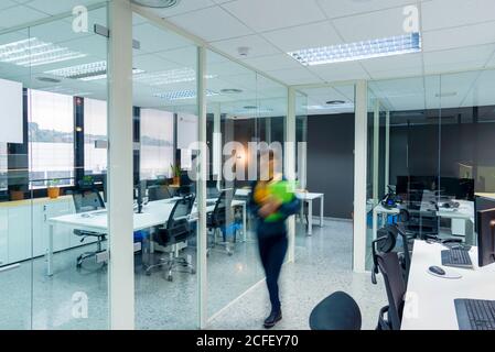 Blurred female carrying folders with documents while walking in modern office Stock Photo