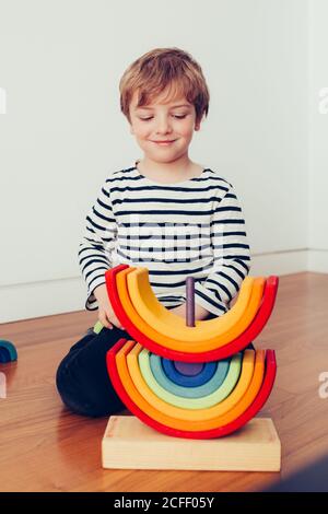 Blonde cute boy playing with waldorf rainbow puzzle Stock Photo