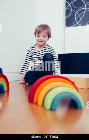 Blonde cute boy playing with waldorf rainbow puzzle Stock Photo