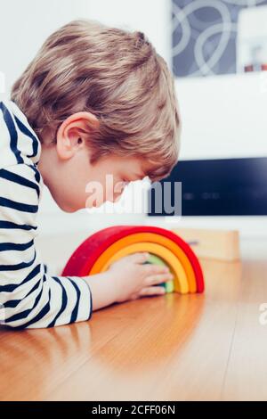 Blonde cute boy playing with waldorf rainbow puzzle Stock Photo