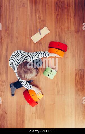 Blonde cute boy playing with waldorf rainbow puzzle Stock Photo